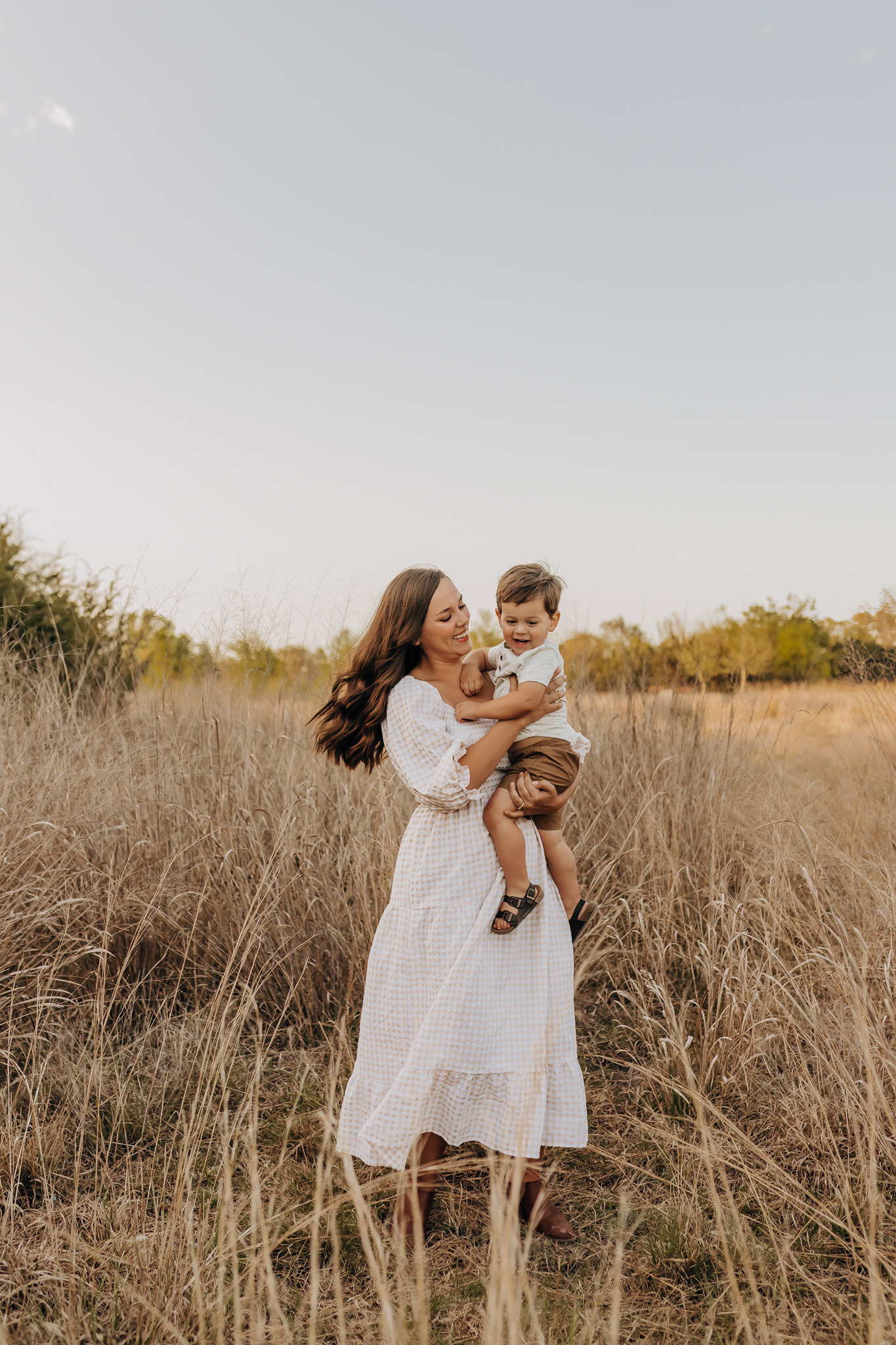 Mom and son walking through a San Antonio grassy field for a sunset photography session.